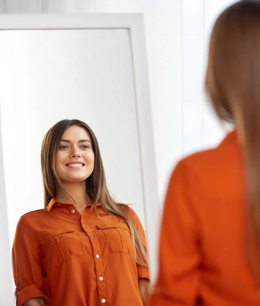 Happy woman looking in the mirror